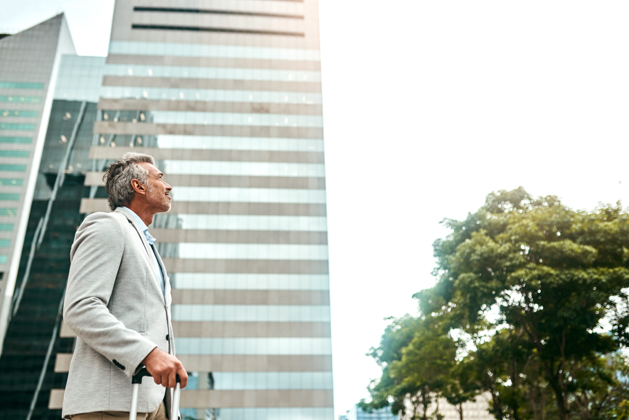 Shot of a mature businessman walking with a suitcase in the city
