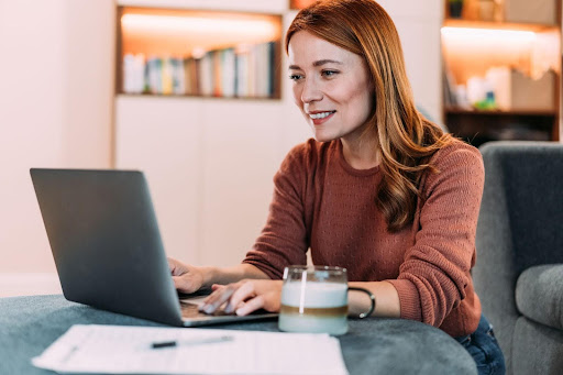 A woman works on her laptop, actively engaging with AI tools and concepts. This image reflects the hands-on, practical agenda of SADA Ground School, demonstrating how participants will gain the skills to make AI work for them.